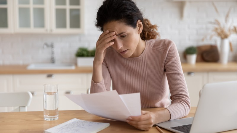 A woman, looking stressed, examines her medical bill.