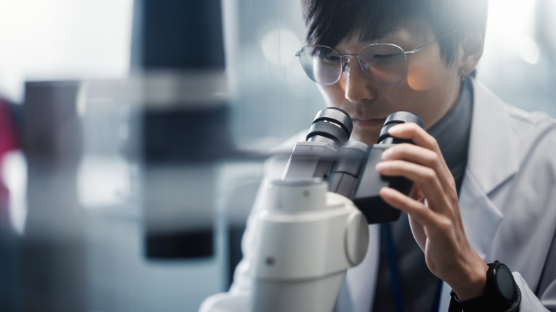 Male scientist looking through microscope