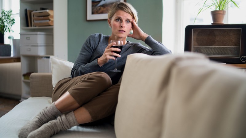 Sad woman drinking alone on couch